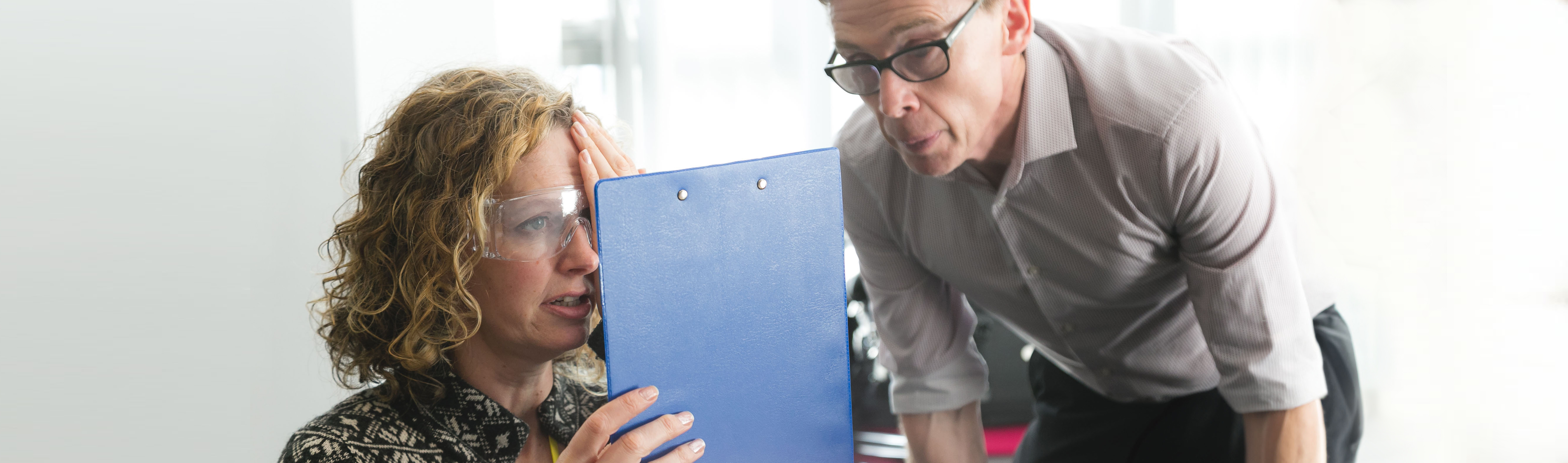 Skills for Seeing - woman wearing glasses with clip board, covering one eye, while a man oversees 