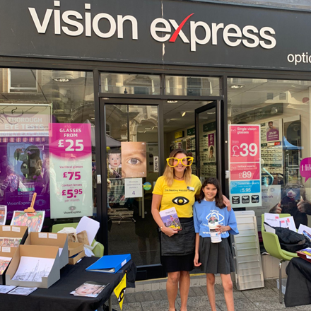 Woman and child outside Vision Express in Macular Society t-shirts