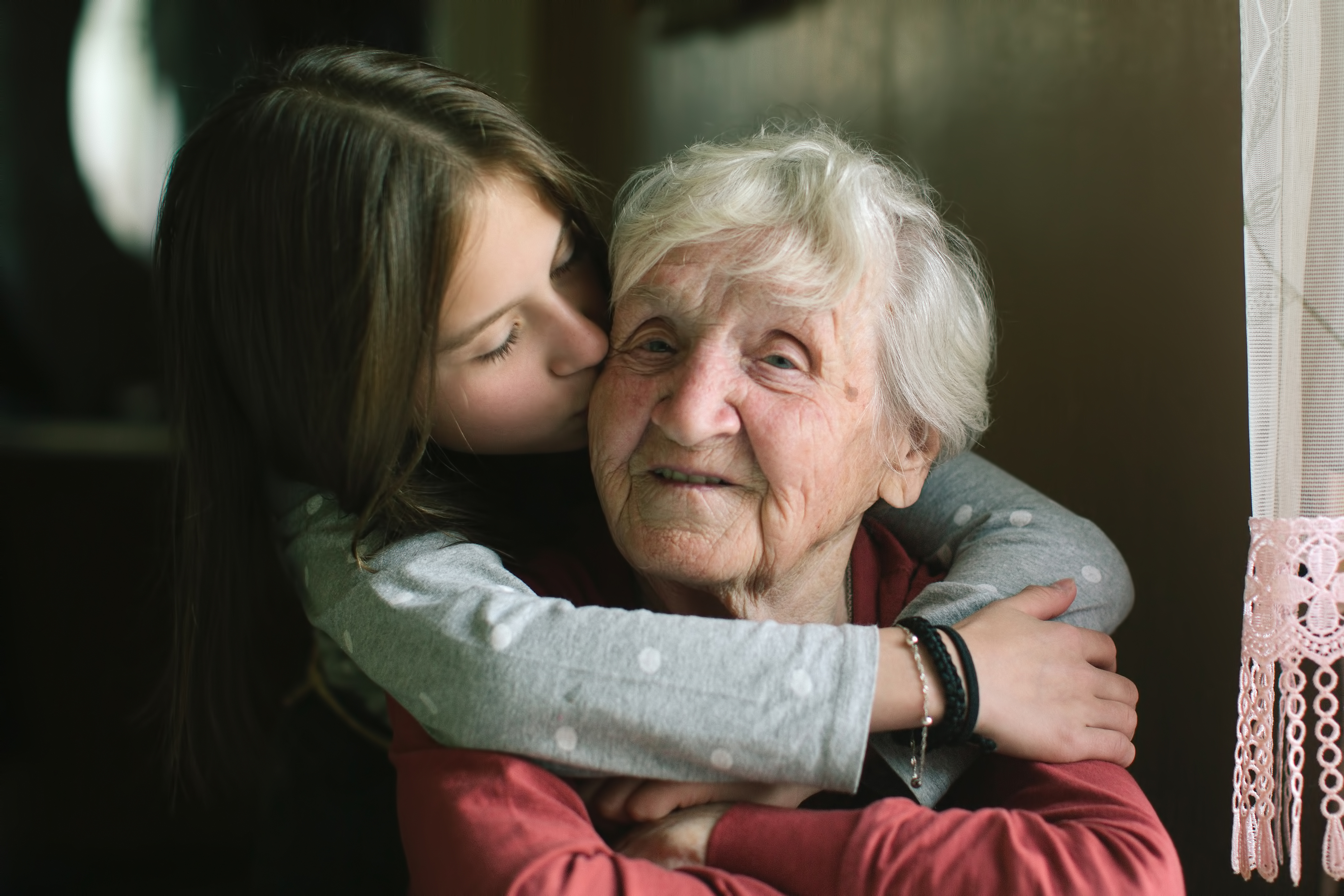 grandmother and granddaughter hugging and kissing cheak