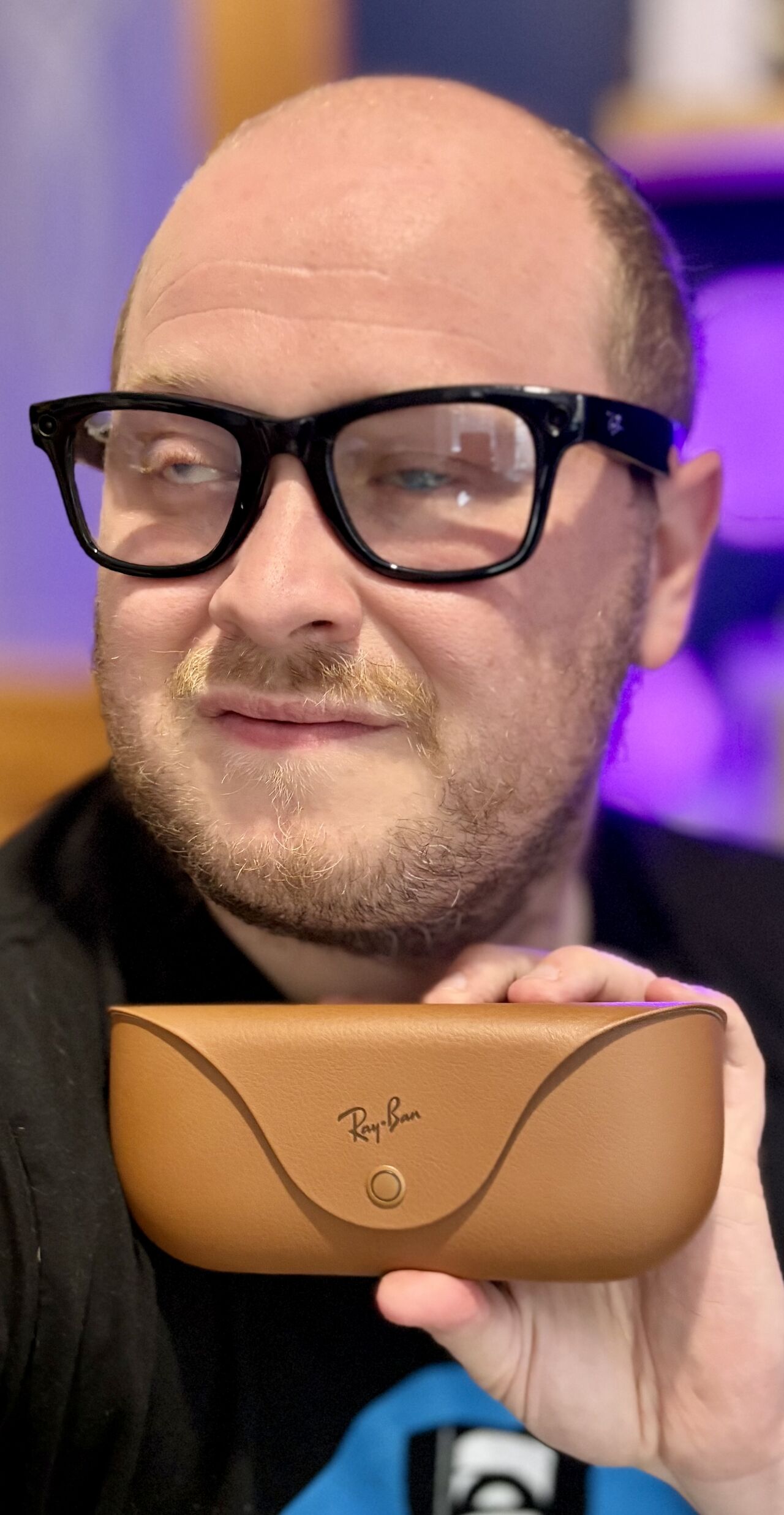 Image of Martin, a white man in his 30s wearing the dark and thick rimmed Meta AI glasses, holding up the case and looking to camera