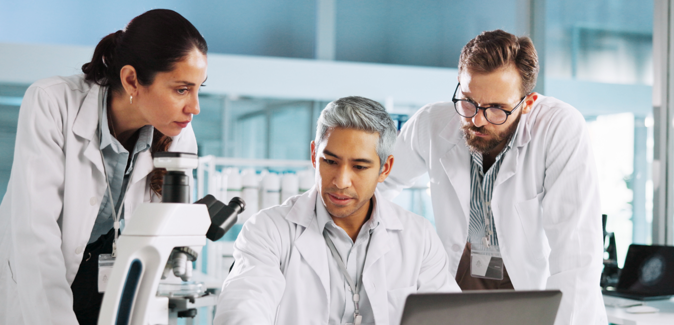 Three researchers with a microscope and laptop in the laboratory