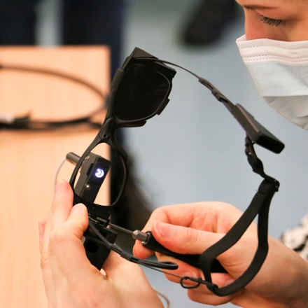 A woman fitting a pair of the black bionic glasses used as part of the PRIMA System