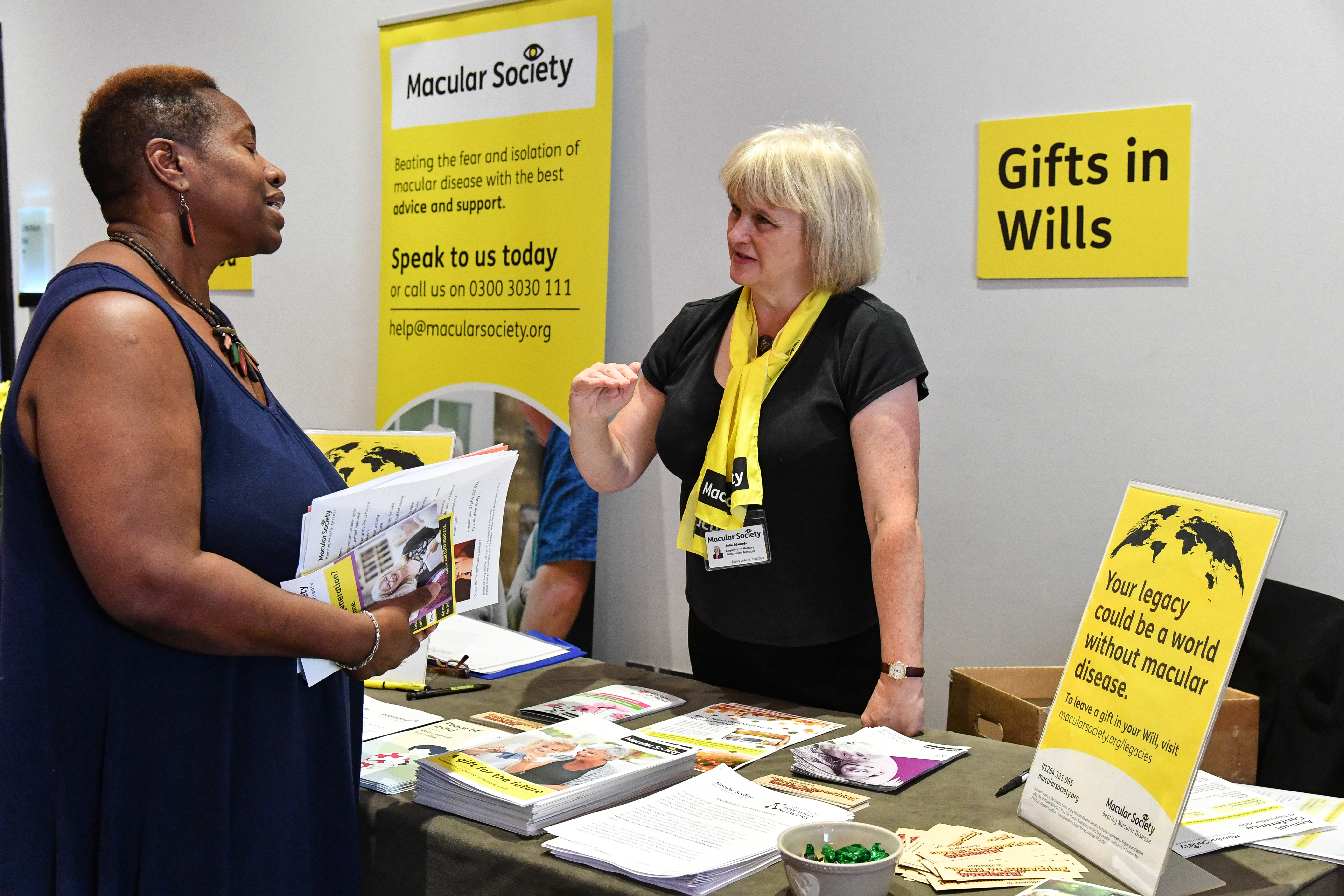 Conference delegate speaking with Macular Society staff at Gifts in Wills table