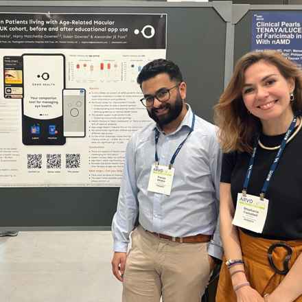 Picture of two Okko Health reps, one white female and one brown male, standing by poster presentation at ARVO 