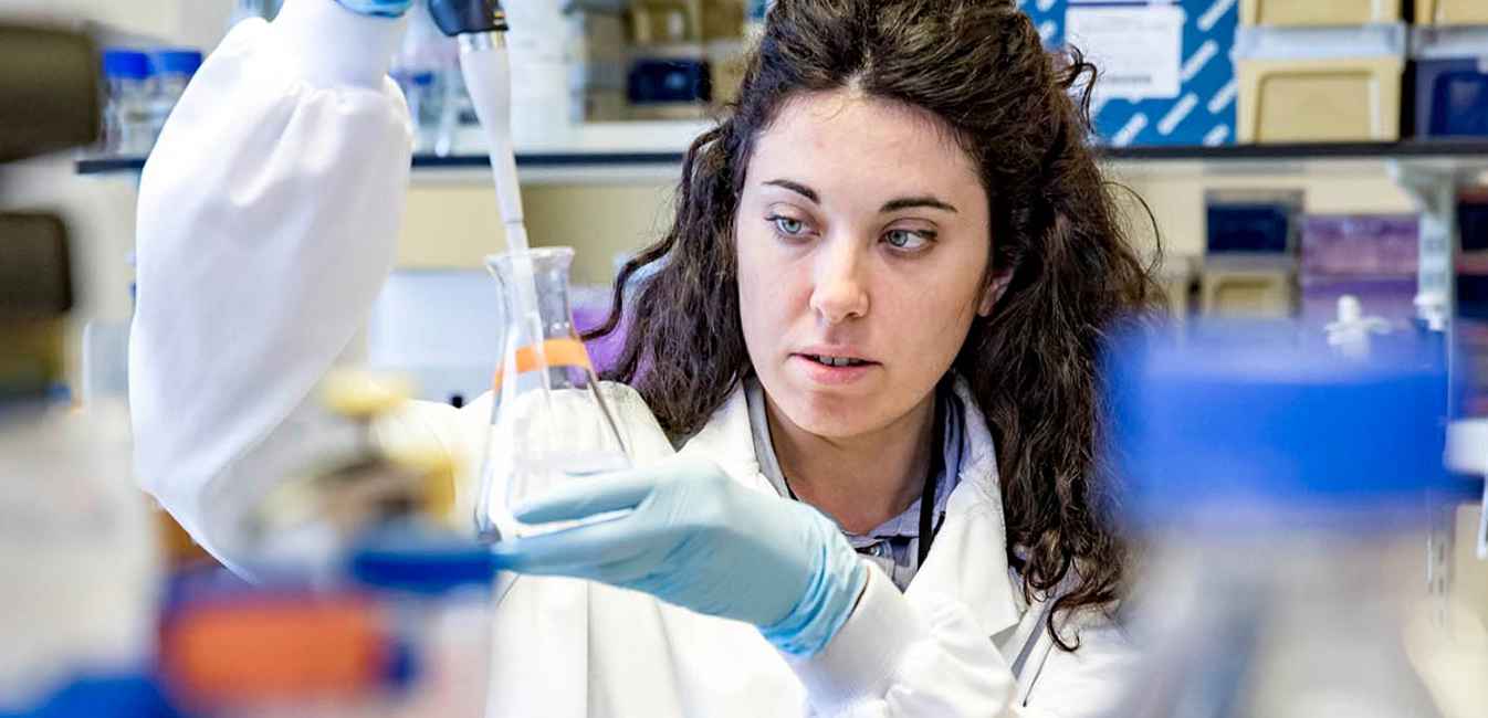 Scientist holding pipette and glass beaker