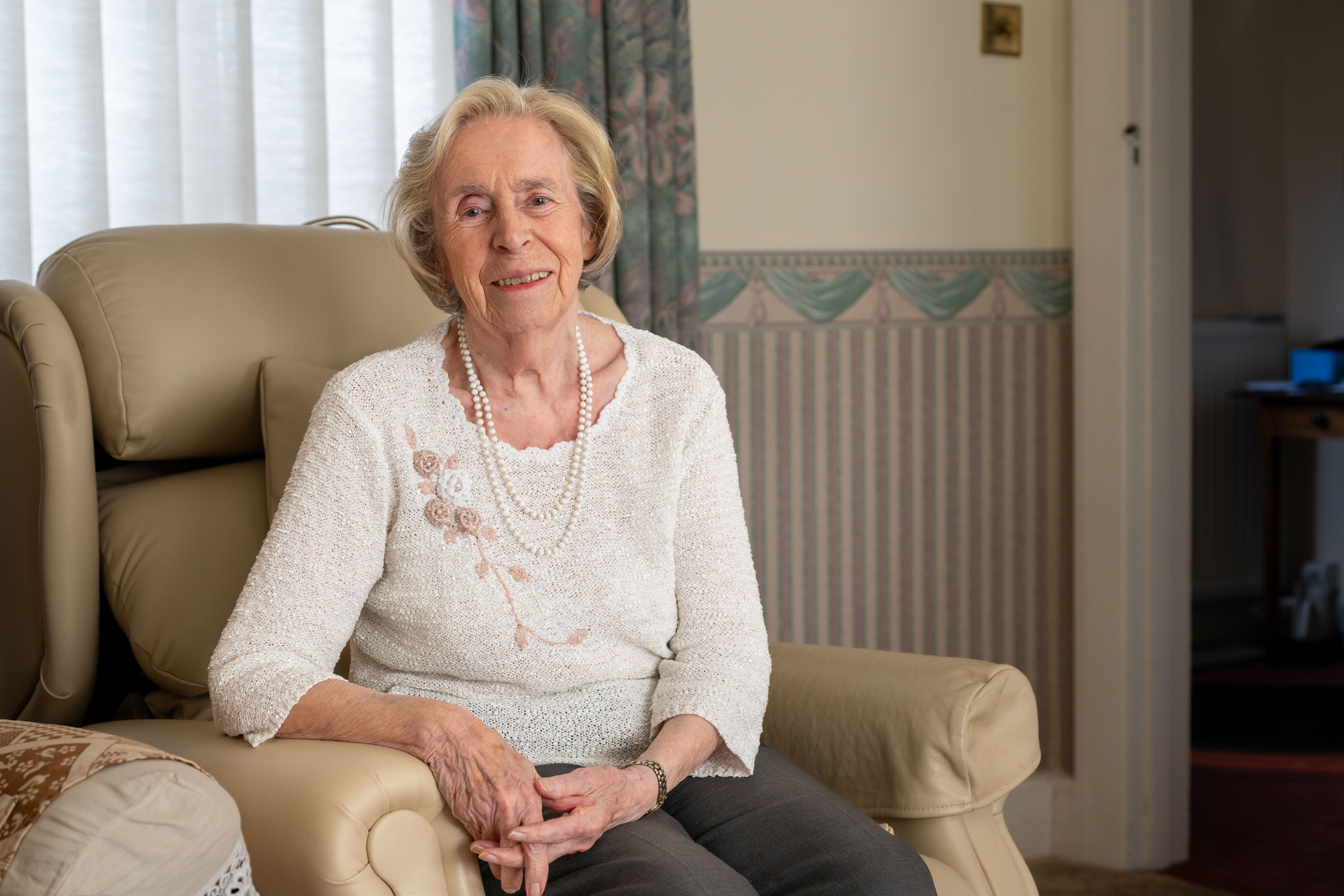 Joan smiling and sitting on a sofa looking to camera