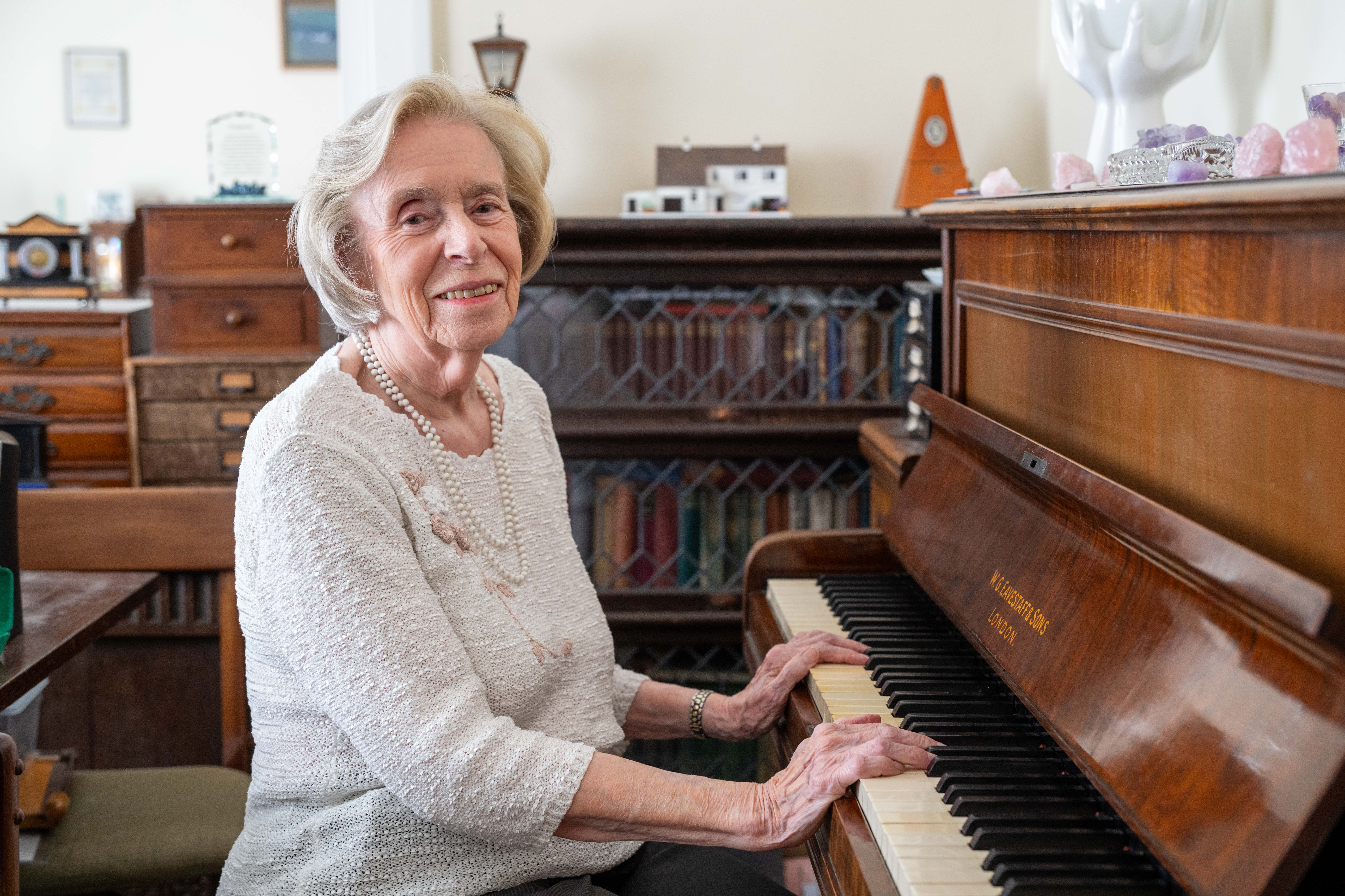 Joan Dyson smiling sitting at her piano