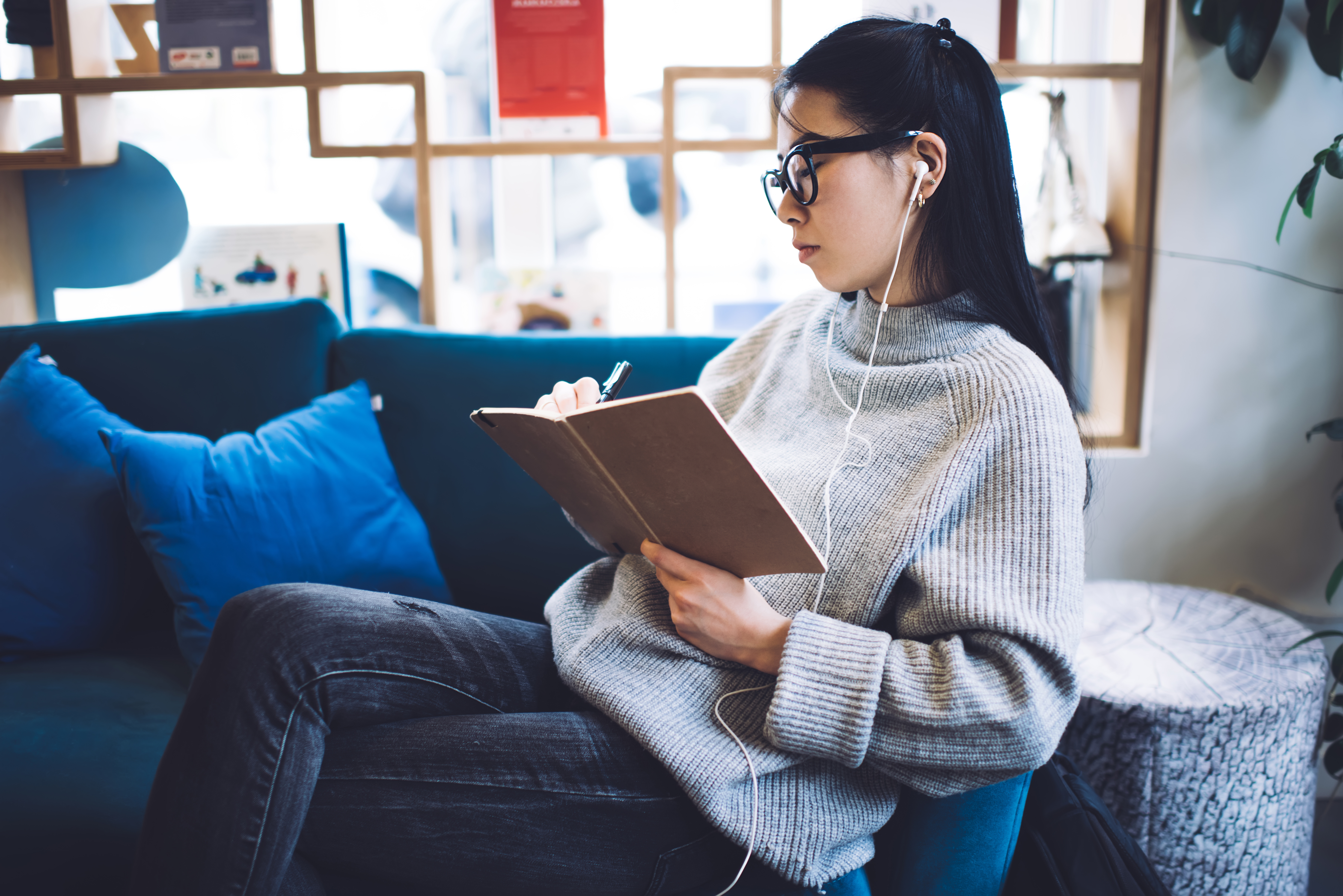 Woman listening to audiobook while writing in book