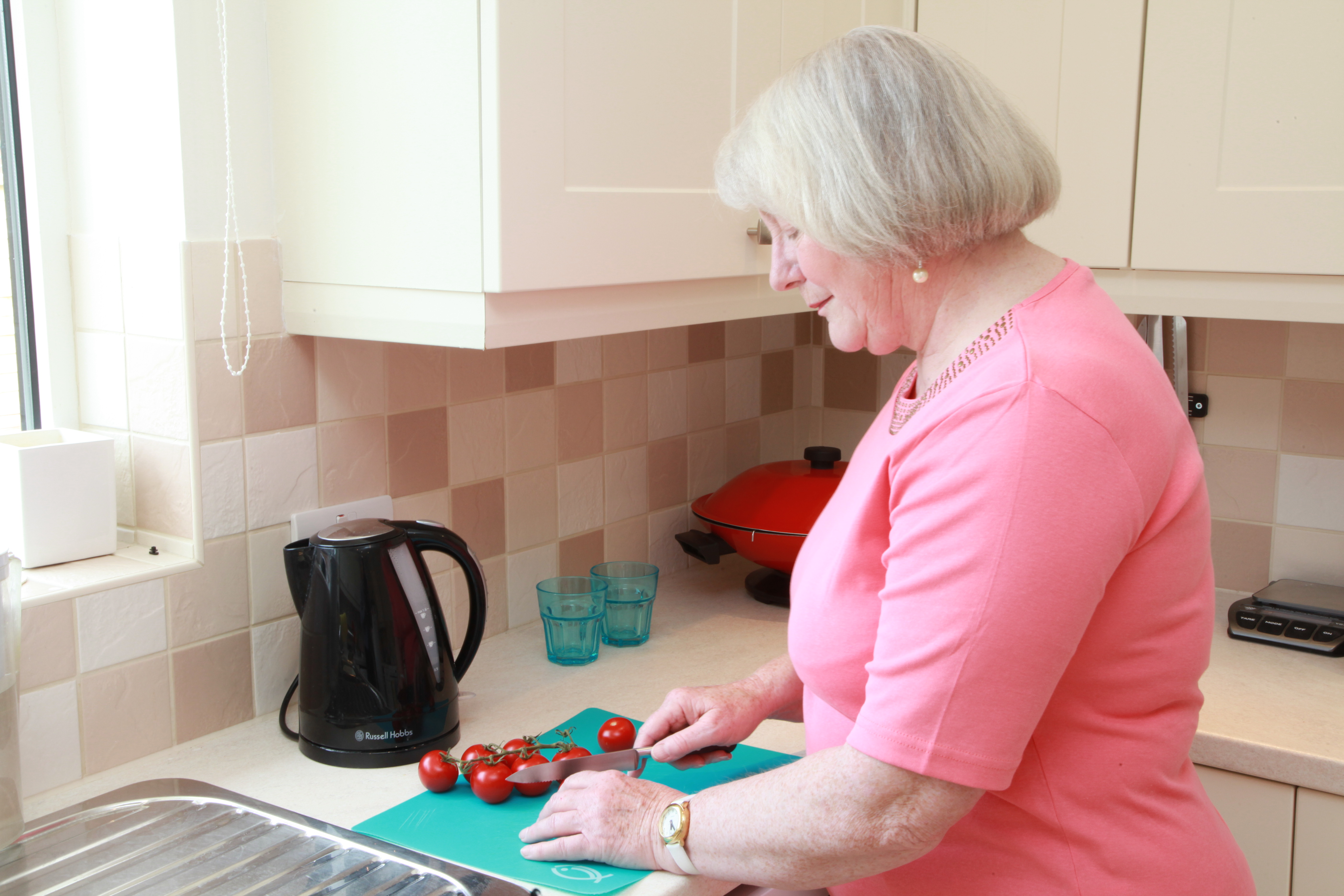 Older lady cutting tomatoes on chopping board