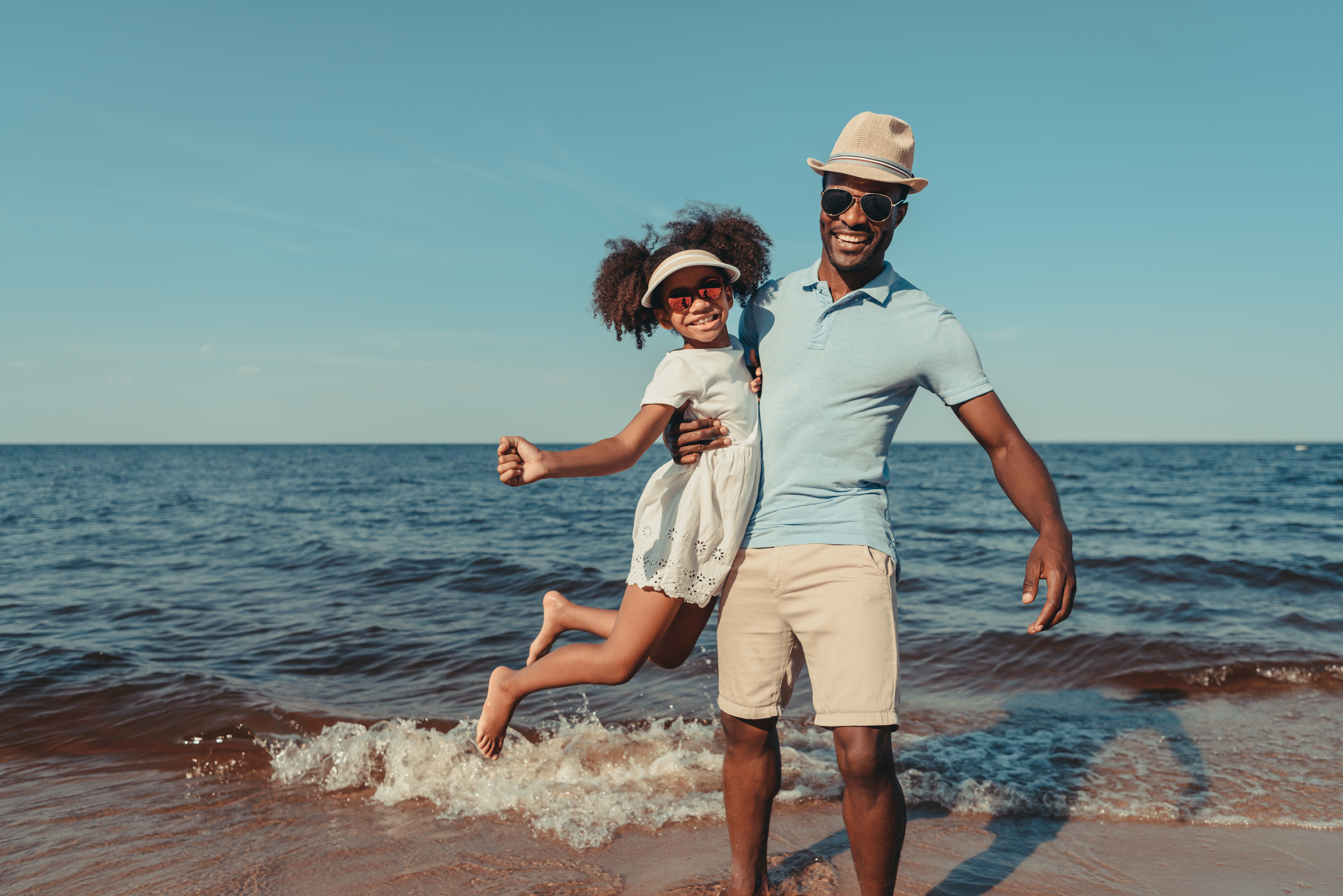 Father and daughter wearing sunglasses on beach