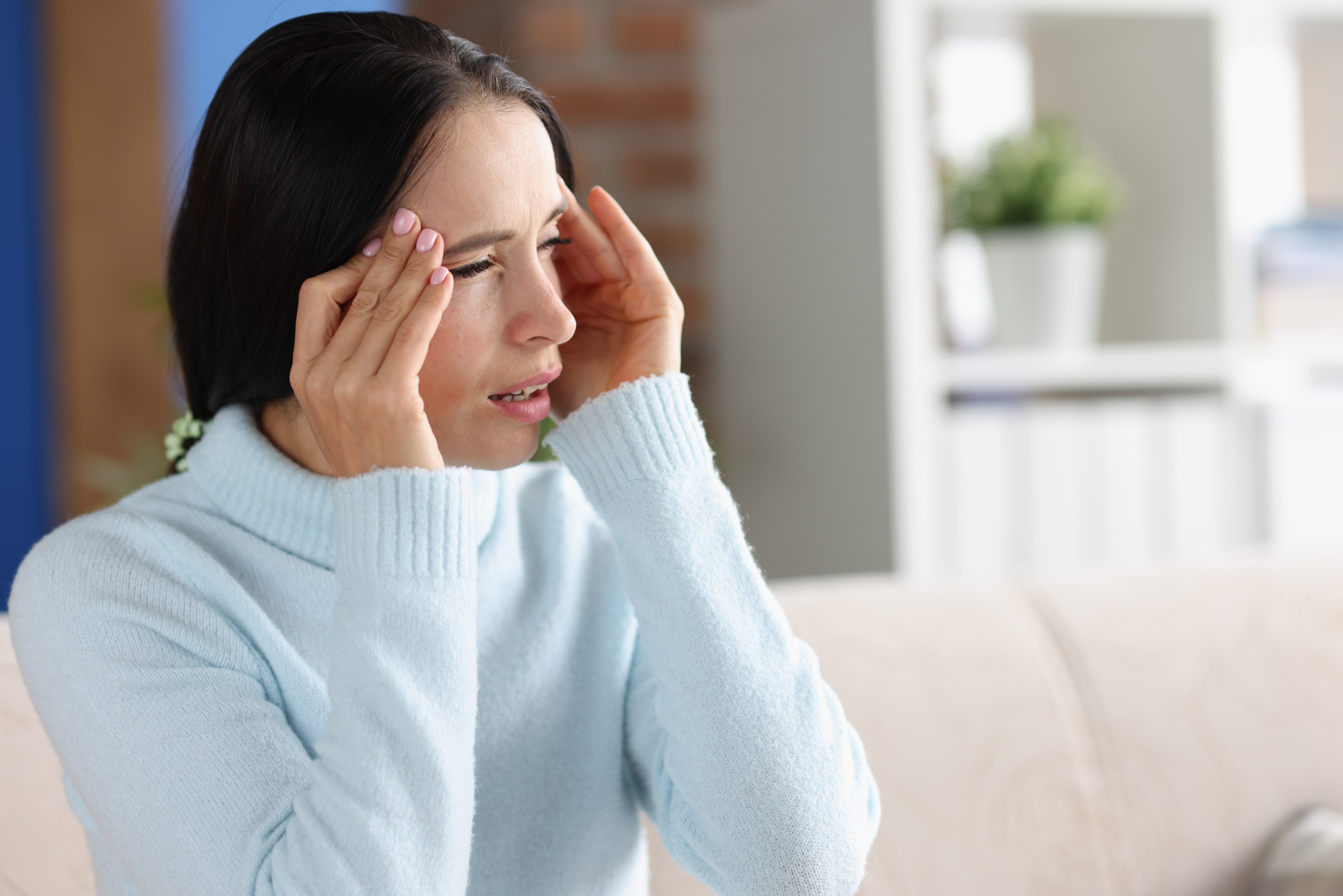 Lady holding her head due to a headache/photophobia